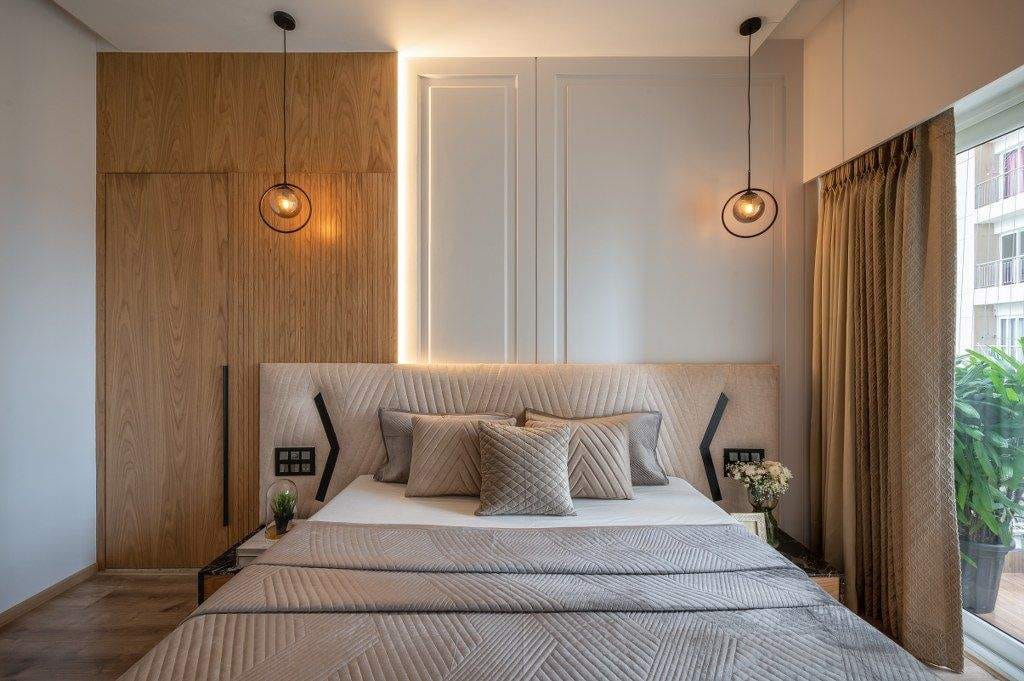 Modern bedroom interior design by Olangana Design in Bangalore featuring a luxurious bed, elegant pendant lights, and sophisticated wall paneling.