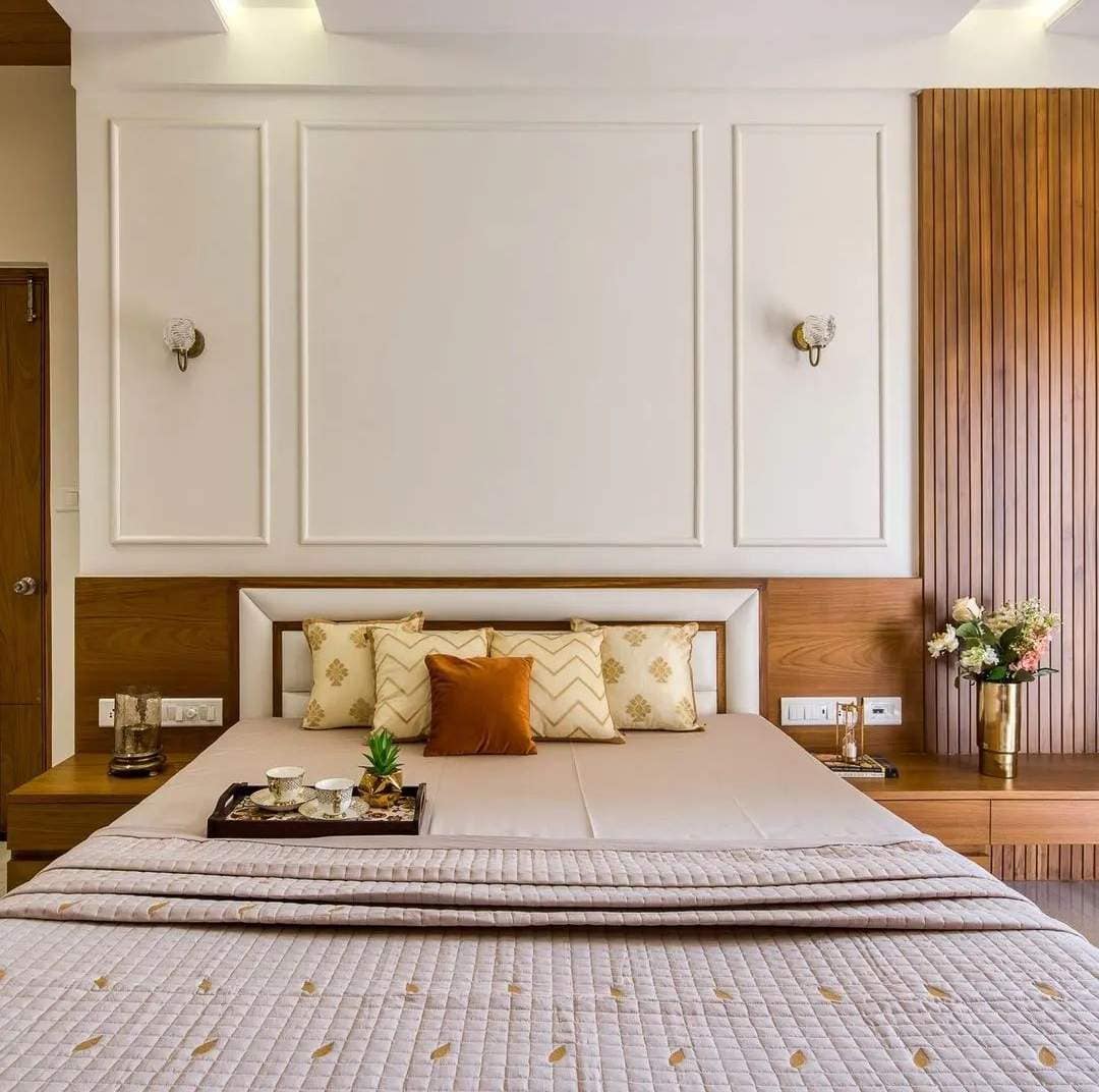 Elegant modern bedroom interior design by Olangana Design in Bangalore featuring a luxurious bed, wooden headboard, stylish wall moldings, and accent lighting.