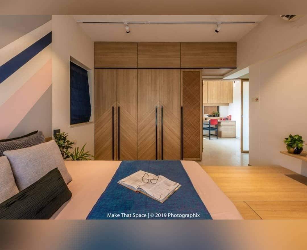 Modern bedroom interior with custom chevron pattern wardrobes, striped accent wall, and adjoining study nook, expertly designed by Olangana Design in Bangalore.