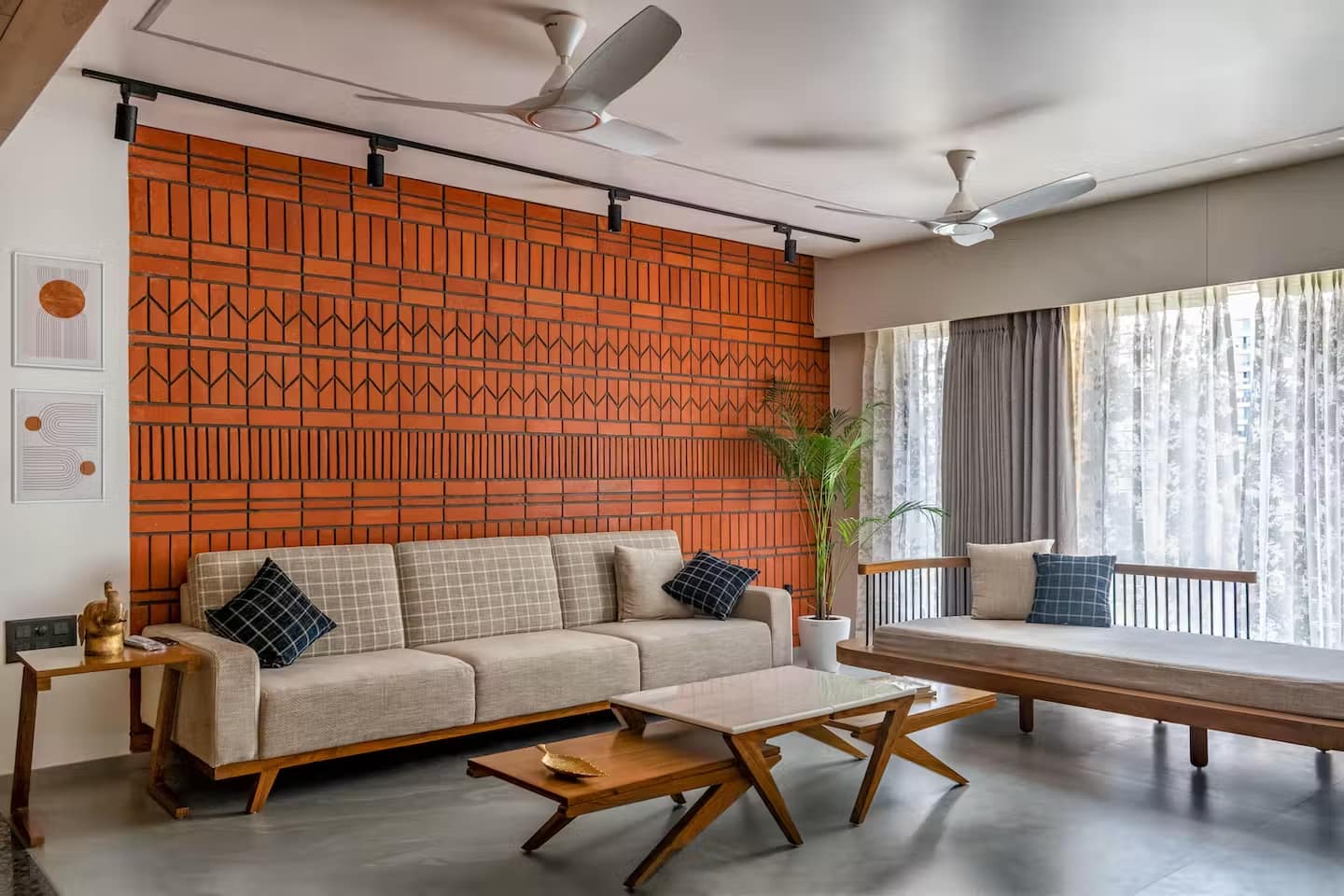 Modern living room interior design by Olangana in Bangalore, featuring a striking terracotta patterned accent wall, a comfortable beige sofa, and elegant wooden nesting coffee tables.