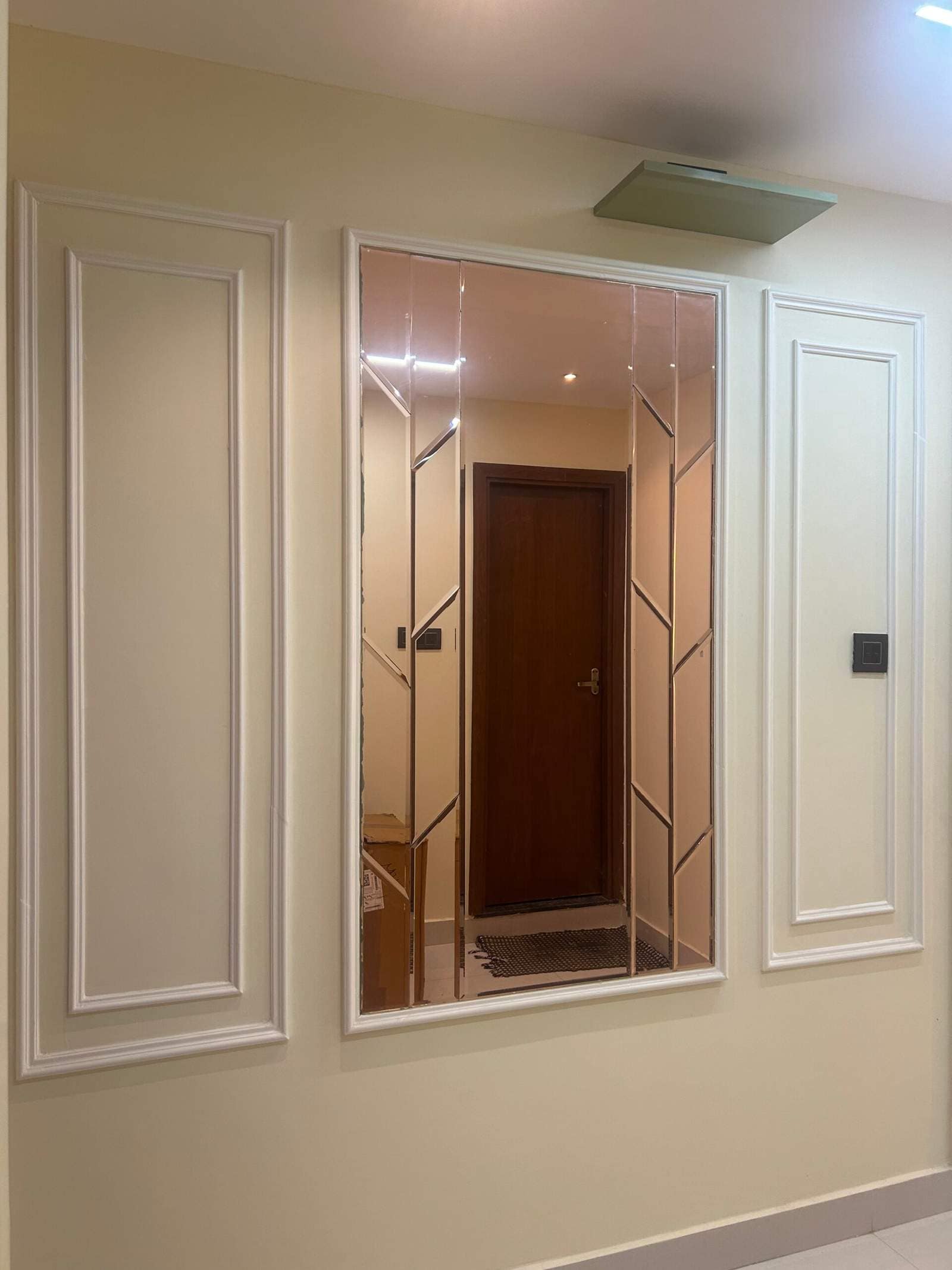 Modern hallway interior with decorative wall moulding panels and mirror wall design designed by Olangana Design’s.