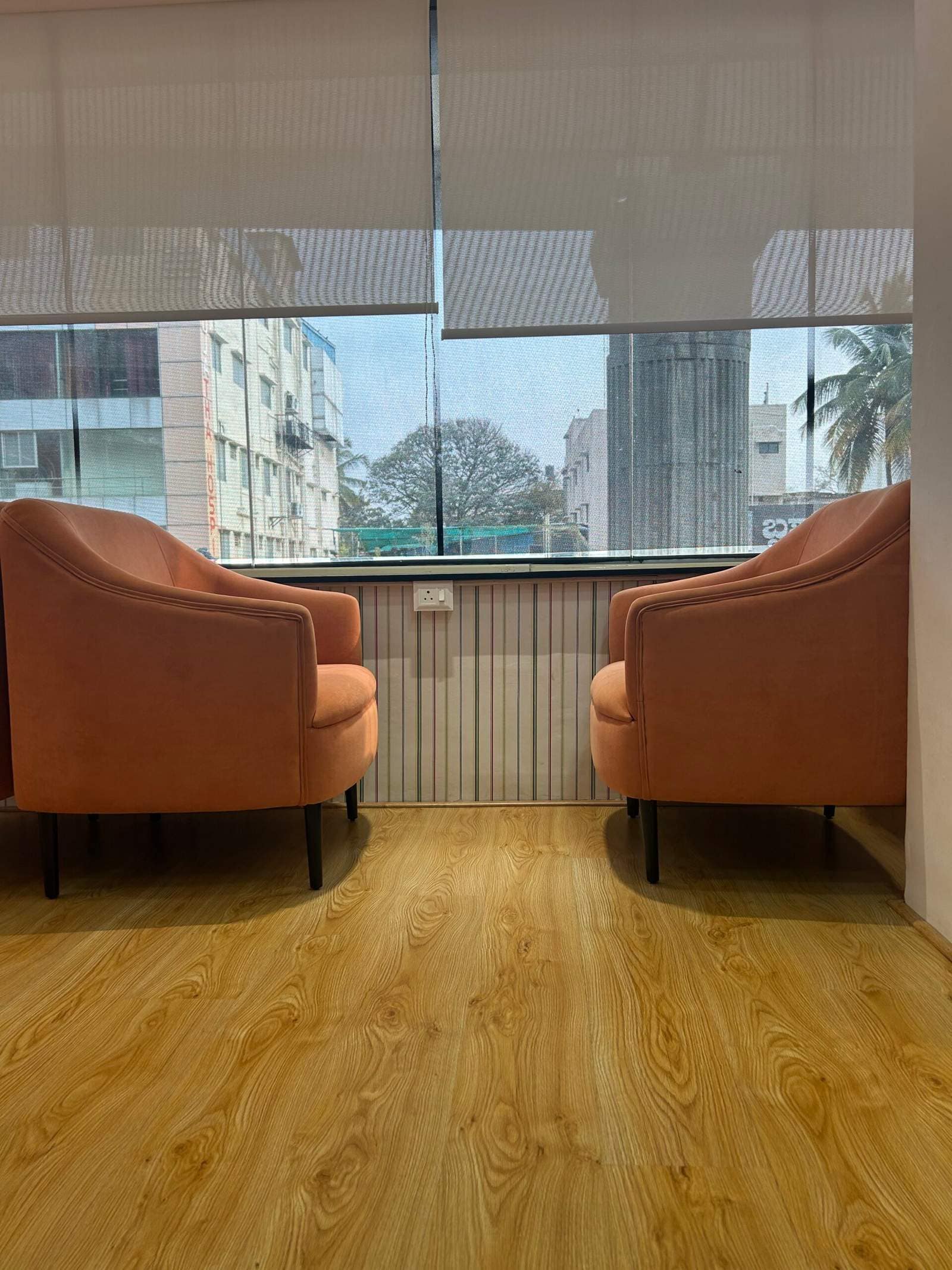 Window side office seating in Bangalore with two opposite sofas for discussion space by Olangana Designs