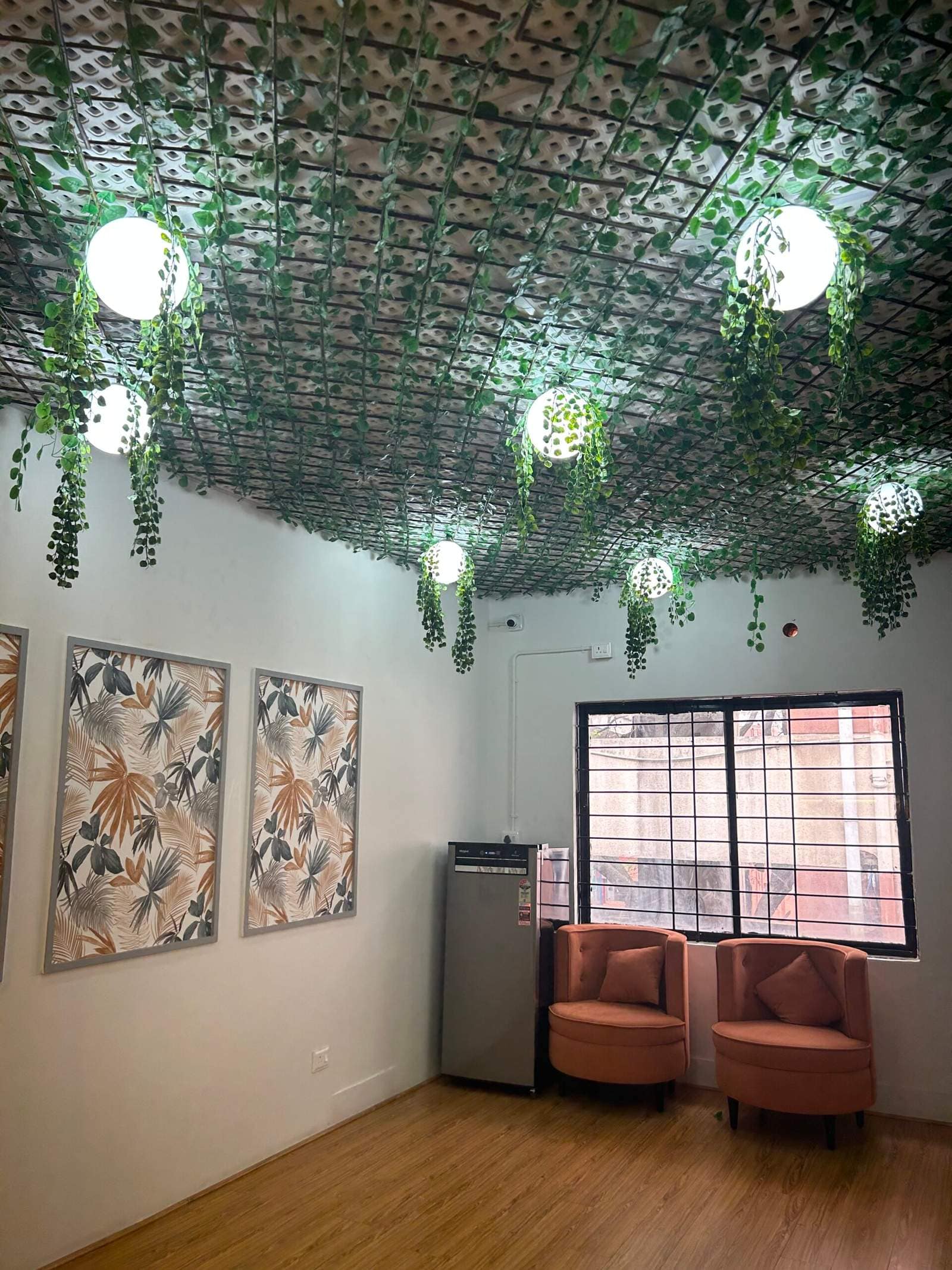 Modern home waiting room interior in Bangalore with green ceiling décor, wooden flooring, and wall art by Olangana Designs
