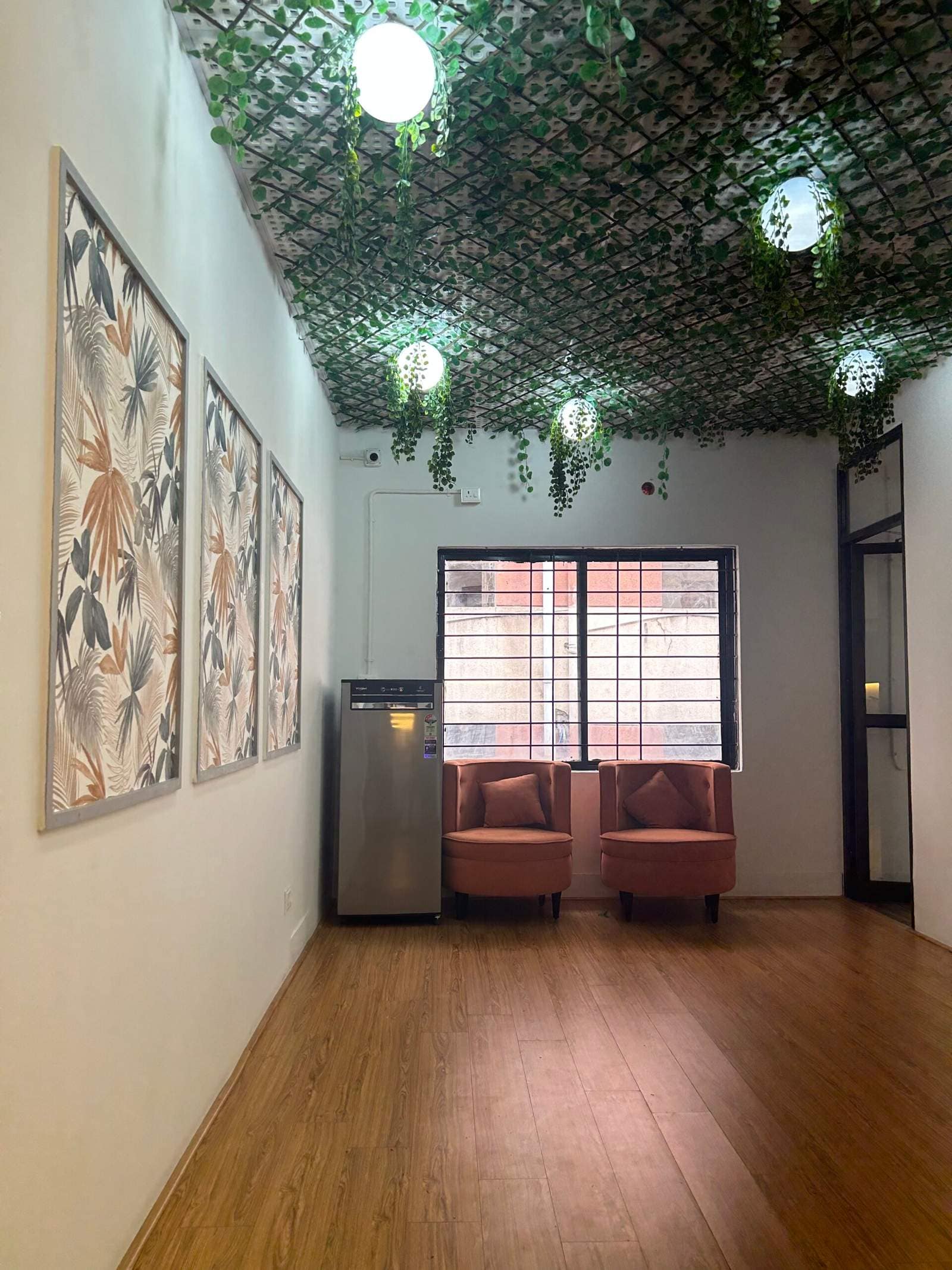 Modern office waiting area in Bangalore with decorative leaf ceiling design and wooden flooring by Olangana Designs