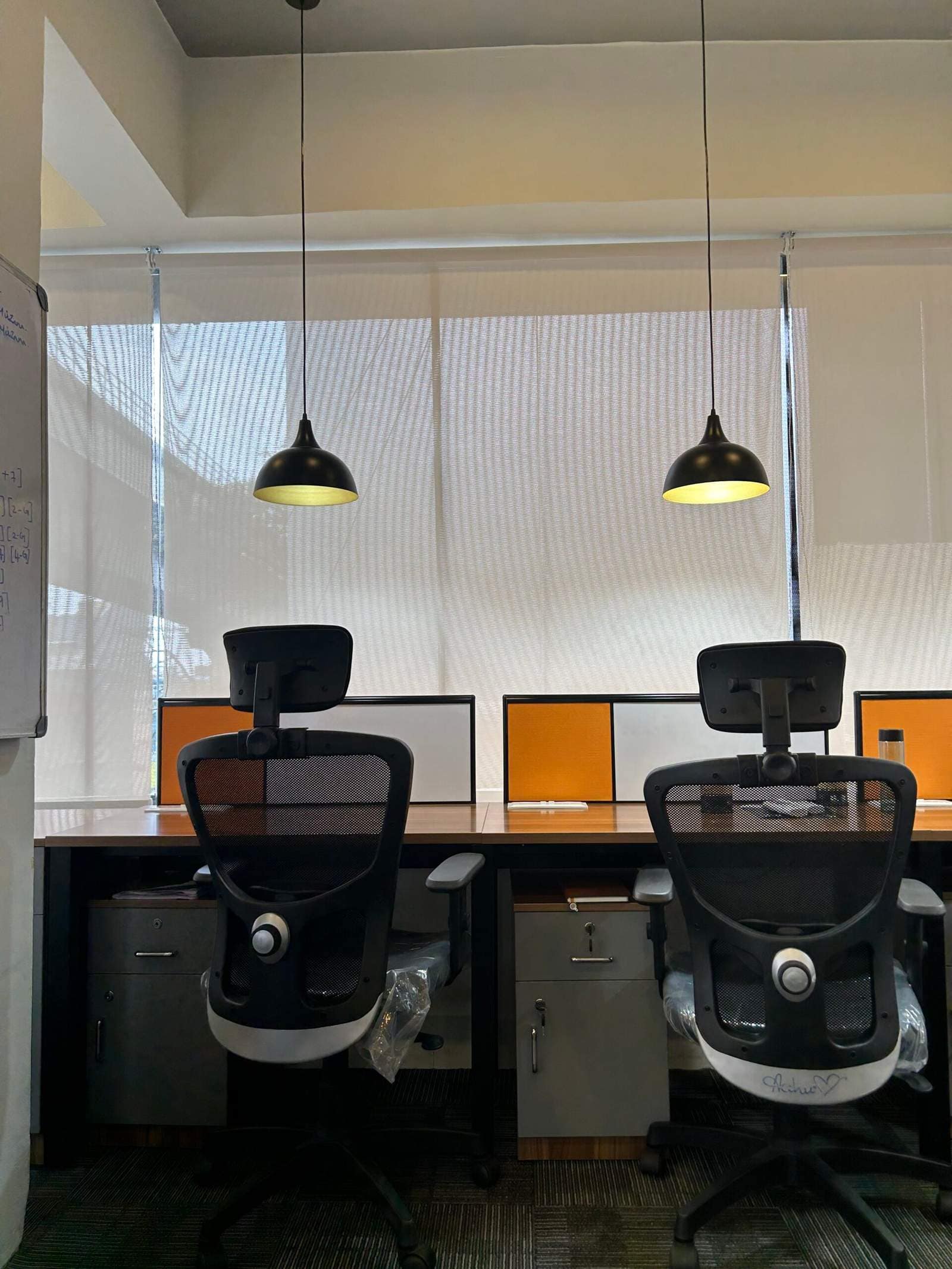 Olangana Design’s small corporate office cabin interior in Bangalore featuring two chairs, desk setup, and modern lamps for a professional workspace.