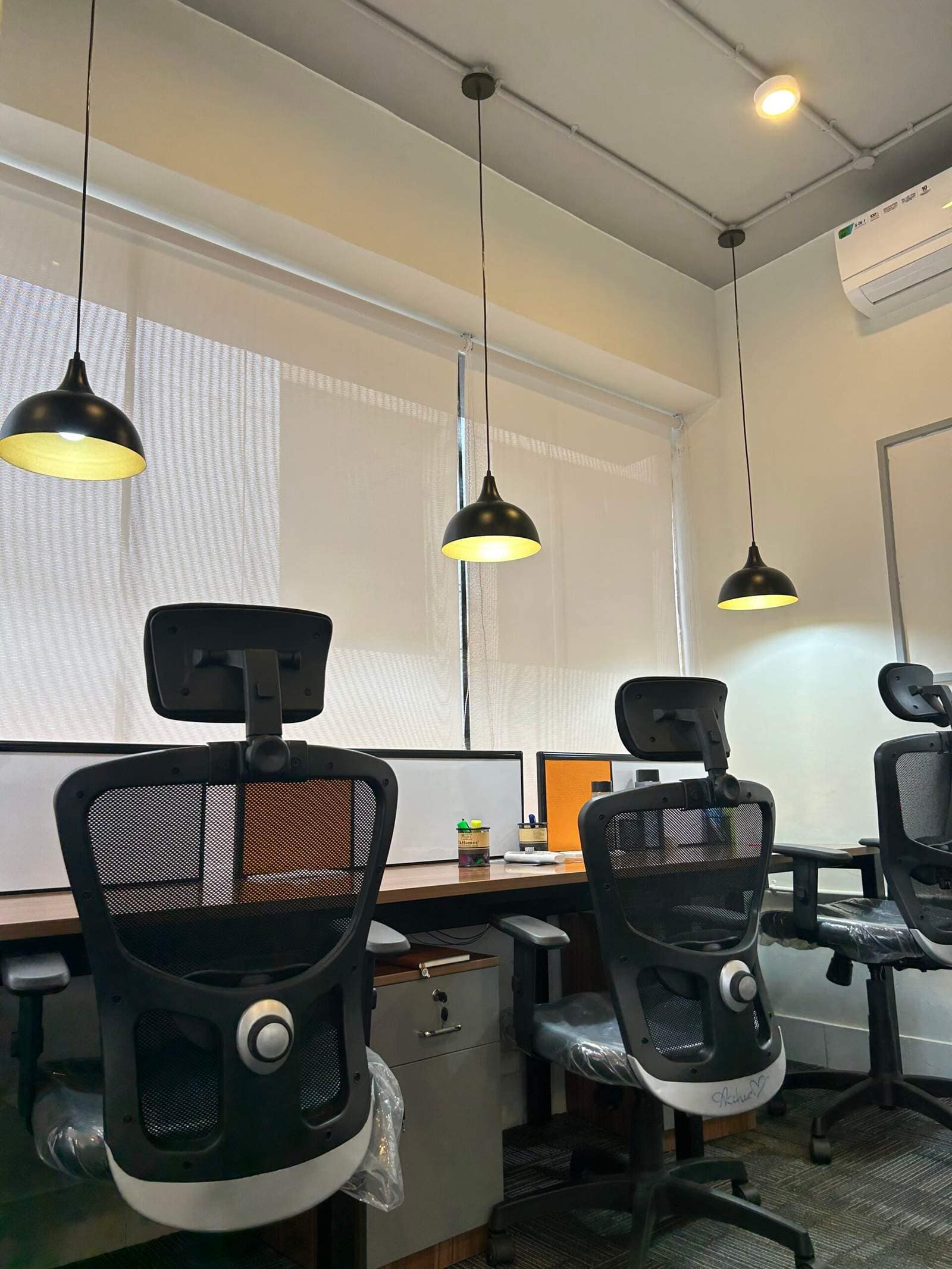 Olangana Design’s small corporate office cabin interior in Bangalore with two chairs, desk lamps, and board for a modern workspace.