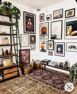 Eclectic living room interior design by Olangana in Bangalore, featuring a vibrant gallery wall, industrial-style shelving, a bohemian rug, and rustic wooden floors.