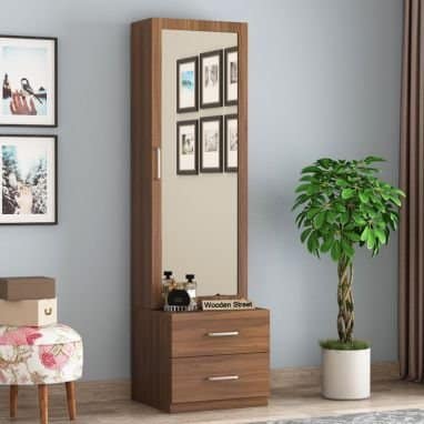 Modern wooden dressing table with full-length mirror and drawers, a floral stool, and a lush green plant, showcasing elegant interior design by Olangana Design in Bangalore.