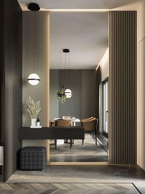 Modern interior design entryway by Olangana Design in Bangalore, featuring a sleek dark console table, stylish pendant lighting, textured wall panels, and a glimpse into a contemporary dining area.