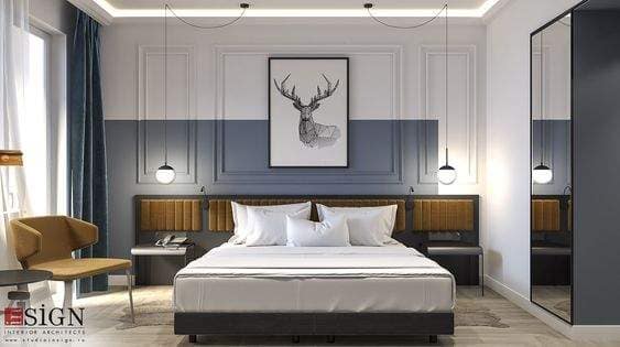 Modern bedroom interior design by Olangana Design in Bangalore, featuring a king-size bed, upholstered headboard, pendant lights, and a deer artwork on a two-tone wall.