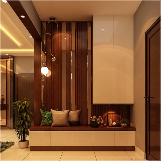 Modern entryway interior design by Olangana Design in Bangalore, featuring sleek storage, a comfortable bench with pillows, decorative wood paneling, and a contemporary pendant light.