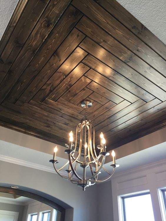 Elegant dark wood herringbone ceiling interior design by Olangana in Bangalore, featuring a classic multi-arm chandelier and sophisticated architectural details.