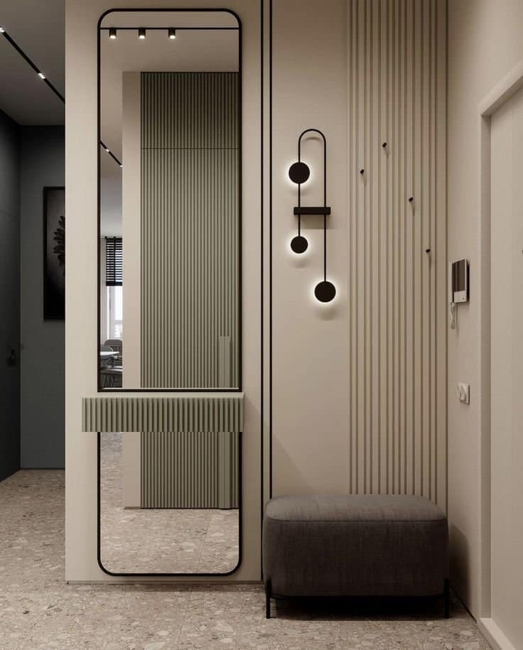 Modern entryway interior design by Olangana Design in Bangalore featuring a full-length mirror, minimalist fluted console, stylish wall lighting, and an upholstered bench, showcasing sophisticated residential interior solutions.