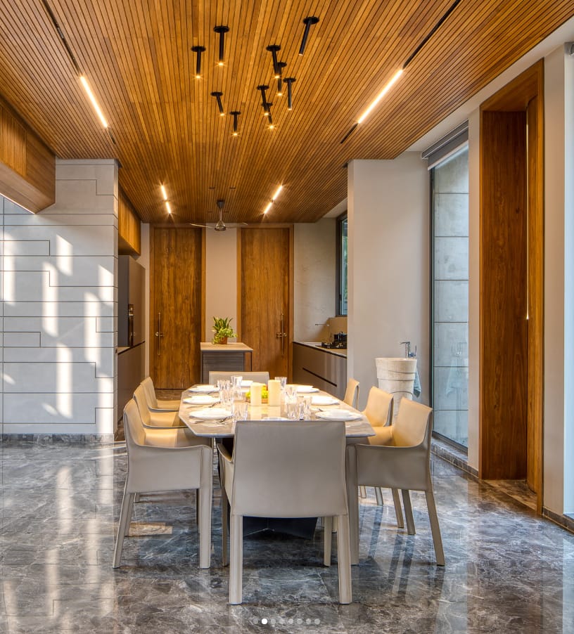 Modern dining room interior design by Olangana Design, featuring a striking wooden ceiling, elegant marble floor, and sophisticated dining set in a Bangalore residence.