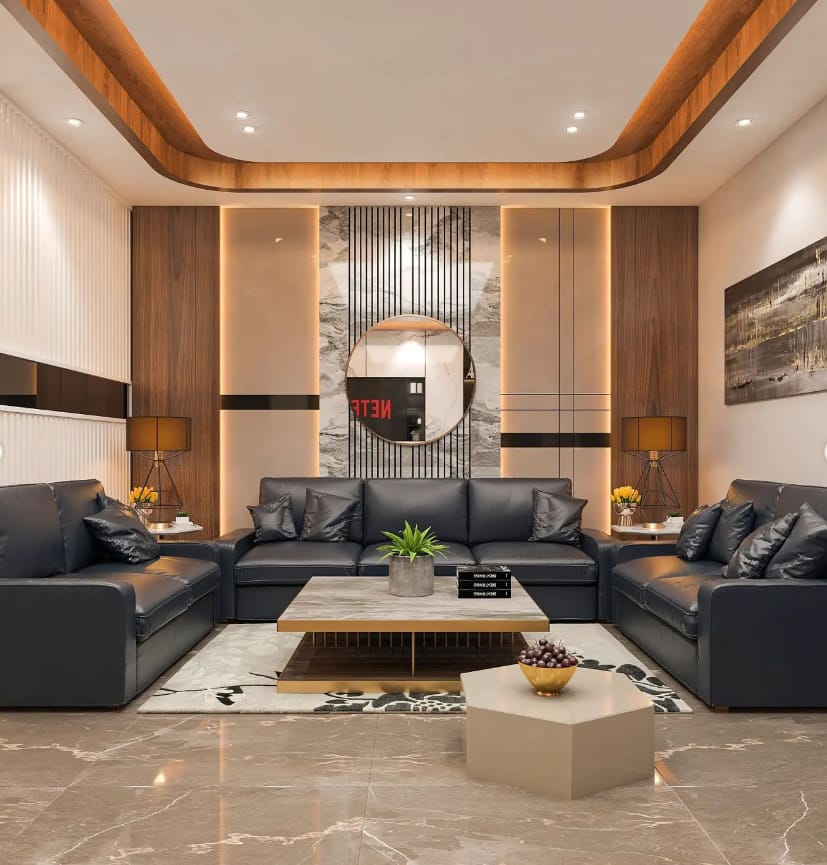 Luxurious modern living room interior design by Olangana in Bangalore, featuring dark leather sofas, a marble coffee table, warm wood paneling, elegant accent lighting, and a striking round mirror.