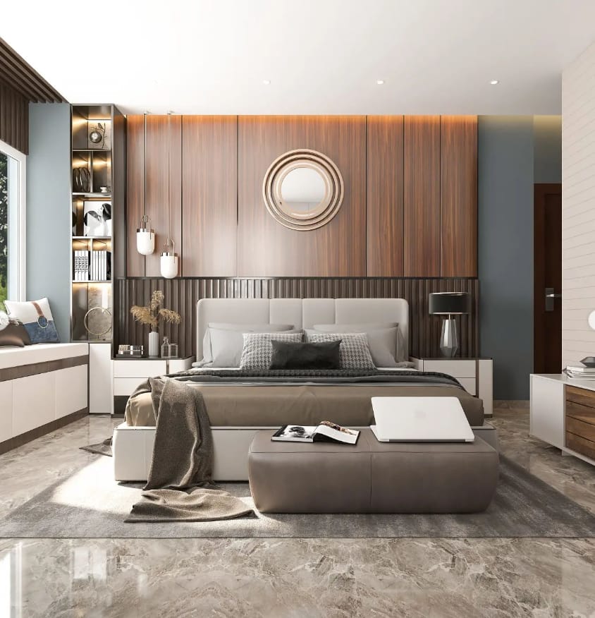 Modern bedroom interior design by Olangana Design in Bangalore featuring a wood panel accent wall, round mirror, upholstered bed, elegant lighting, and a cozy window seat.
