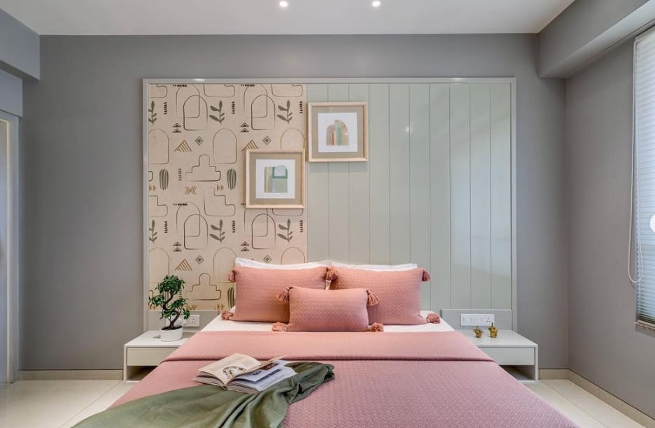 Modern bedroom interior by Olangana Design in Bangalore featuring a pink bed with tassel pillows, a unique split headboard with abstract wallpaper and green paneling, floating nightstands, and minimalist decor, showcasing elegant residential interior design.