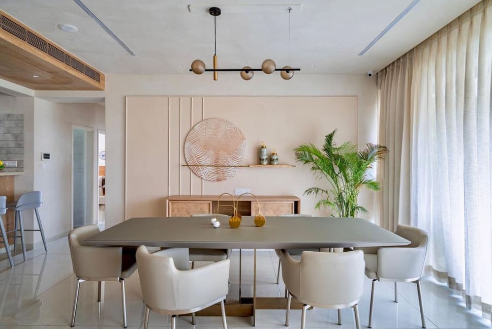 Modern dining room interior design by Olangana Design in Bangalore, showcasing a contemporary table, upholstered chairs, statement chandelier, and sophisticated wall decor.